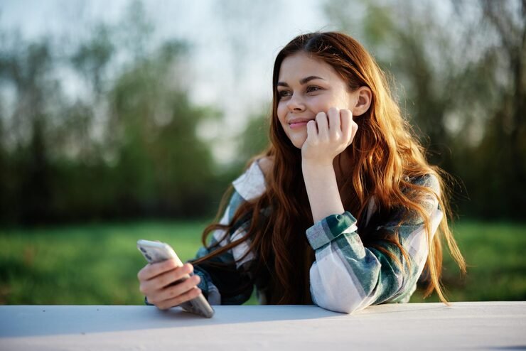 Young woman thinking about someone special and smiling at her phone